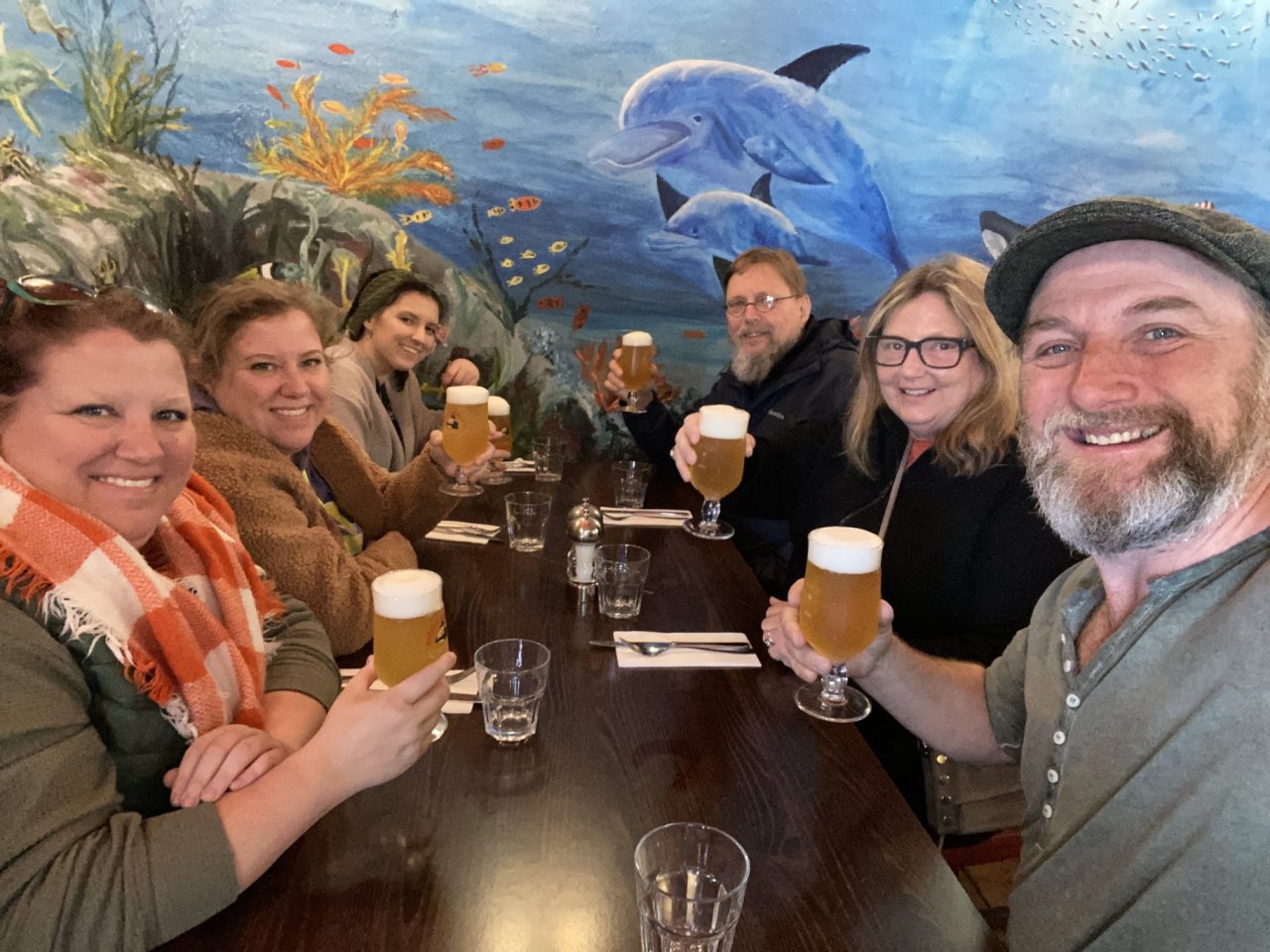 six people at a table with pints in their hand